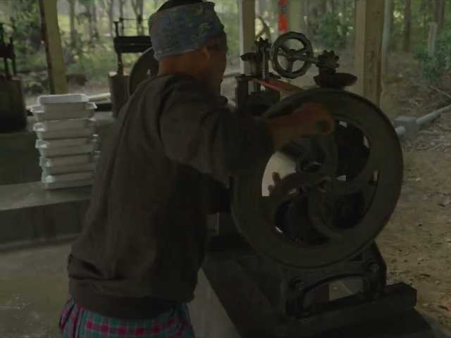A worker turning the sheet press by hand on site.